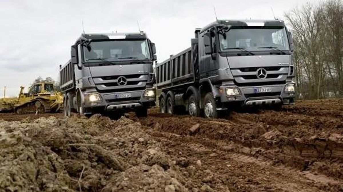 To sølvgrå merchedes lastebiler på arbeidsplass