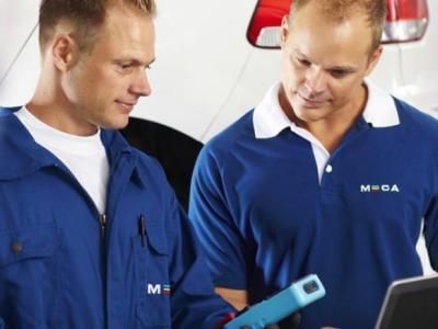 To menn i blå arbeidsdresser med Meca logo som ser ned 