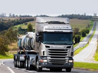 Motgående grå Scania lastebil gjennom grønt landskap