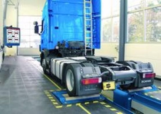 Blå lastebil med tomt lasteplan inne i verksted